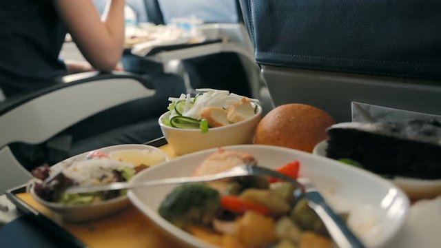 Passenger eats food on Board the plane. Food served on board of business class airplane on the table. Tray of food in the airplane. Tray of food on the plane, business class travel.