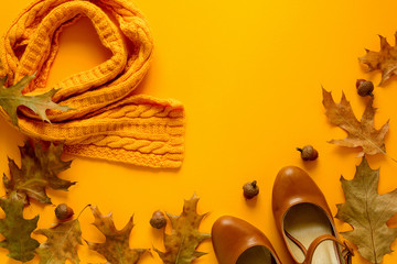 Feminine autumn accessories. Scarf and shoes, cup of coffee, oak leaves and acorns on yellow paper...