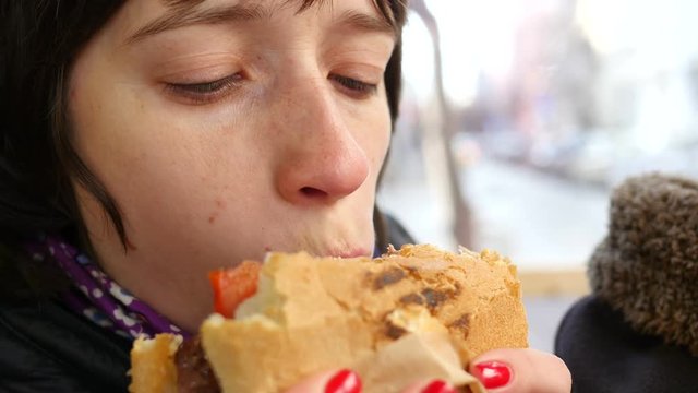 Woman eating big fresh juicy burger in a street fast food closeup