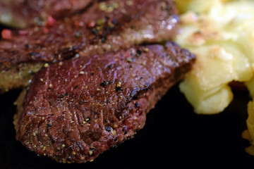 Fried peppercorns spiced steak and gratin potatoes. Close up image with copy space.