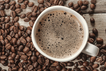 Cup of coffee and beans on wooden background