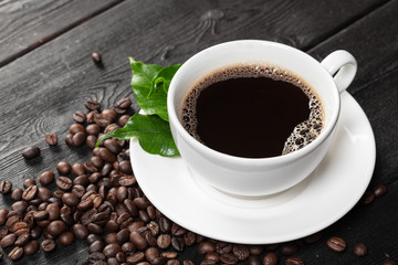 Cup of coffee and beans on wooden background