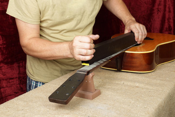 Guitar repair and service - Worker grinds nat guitar neck frets