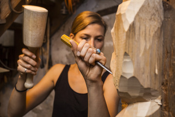 Sculptress carving wooden figure