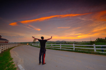 Fototapeta premium Successful man raising arms after cross track running on sunrise. Fitness male athlete with arms up celebrating success and goals after sport exercising and working out.