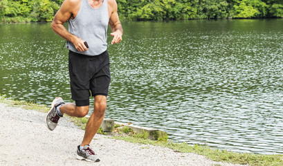 runner with a phone for music passing a lake in the woods