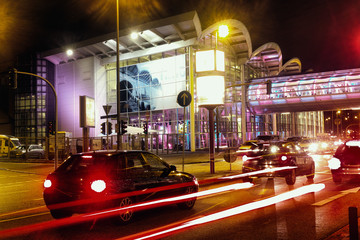 Car driving night stop traffic asphalt concrete black orange background hamburg fair hall - Powered by Adobe