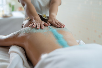 Young beautiful Asian woman relaxing in the spa massage and having salt scrub massage at back....