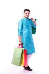Indian man in ethnic wear with shopping bags, isolated over white background