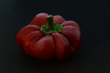 Red hot pepper shaped as pumpkin on black background 