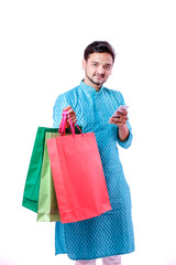 Indian man in ethnic wear with shopping bags and showing mobile screen , isolated over white background