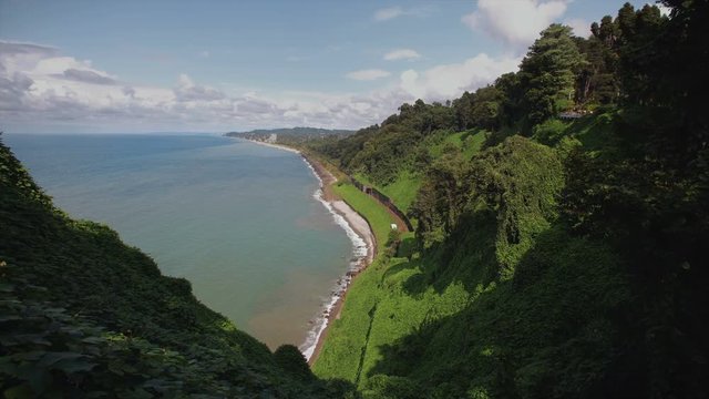 Mountains with tropical trees bushes, cliff to stone beach railway tracks and tunnel botanical garden on hilly locality