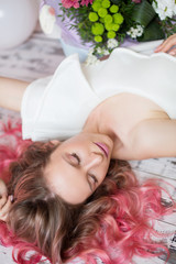Obraz na płótnie Canvas Beautiful girl with pink hair is lying on the floor. Studio shooting