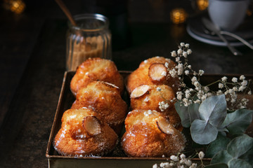 Freshly baked vanilla muffins with sugar powder and coffee on dark background, selective focus. Homemade bakery. Romantic concept. Horizontal.