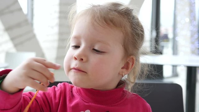 Cute little child girl eating vegetables instead of meat in fast food cort