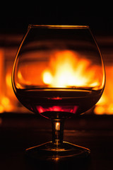 glass of cognac in front of fireplace