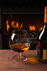 glass of cognac in front of fireplace