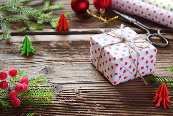 Gift wrapping. Christmas composition with present box, packing paper, festive decoration and fir tree branch. Preparation for holiday. Merry Christmas and Happy New Year concept.