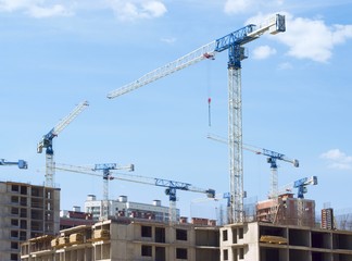 High construction cranes on a construction site against a blue sky