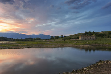 Colorful, spectacular sunset over Balkan mountain, artificial lake Jrebchevo and abandoned, ruined church. Last rays of light. Landscape, background.