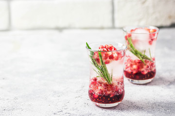 Rosemary pomegranate champagne cocktail with ice cubes. Selective focus, space for text.