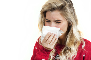 Symptoms of flu or allergies. Strong young European woman with fever, sneezing in a tissue, allergy, cold, with copy space, young girl, portrait of a sick woman, isolated on a white background.