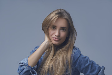 Young woman with beauty skin and beauty hairstyle in jeans jacket isolated on blue background. Studio shot.