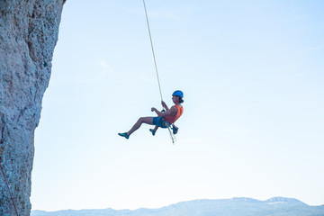 View of man in hardhat hanging on rope while doing rappel and showing pirouettes flying in air  © pablobenii