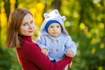 mother and son for a walk in the park. Red-haired girl holds the boy in her arms