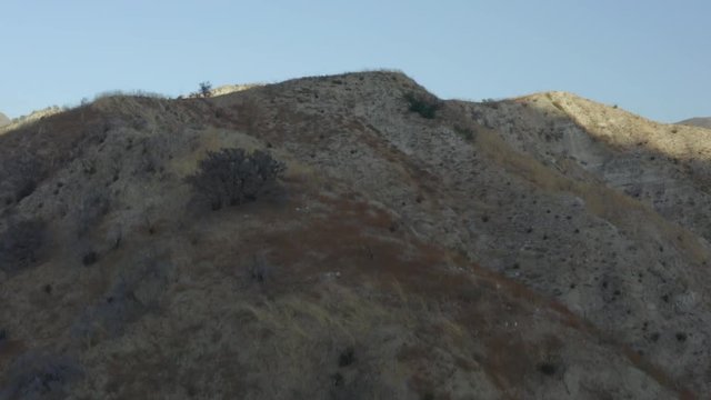 Aerial reveal of a barren mountainous landscape in the desert.