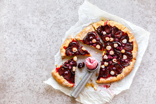 Open Pie Galette with a ball of Strawberry Ice Cream. Cake Season Summer with berries and fruits. Sweet Dessert on the Gray Background with Raspberry and Plum.Copy space for Text. selective focus.