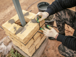 The worker is laying bricks on the fence