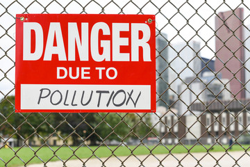  Sign danger due to pollution hanging on the fence