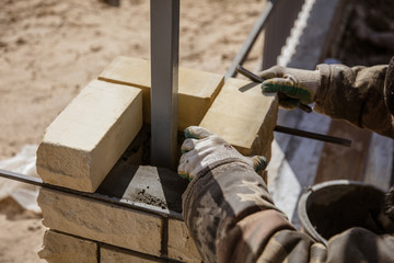 The worker is laying bricks on the fence
