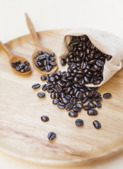 Roasted coffee beans in canvas bag on wooden tray