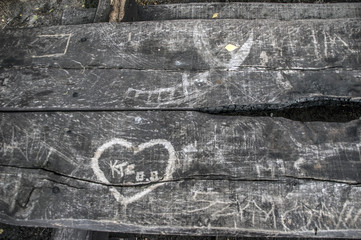 napisy wydrapane lub wypalone na starej drewnianej ławie parkowej 