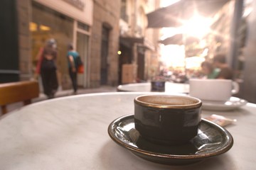 Coffee cup on the table with people in coffee shop sun background