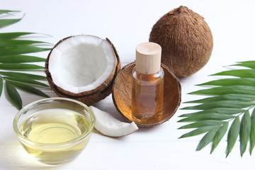coconuts and coconut oil with tropical leaves on a wooden background