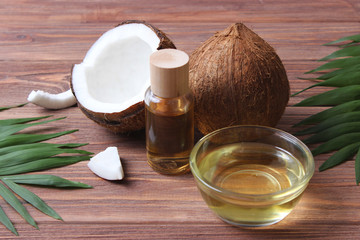 Fototapeta na wymiar coconuts and coconut oil with tropical leaves on a wooden background