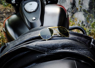 sunglasses on a leather jacket on a motorcycle seat close-up