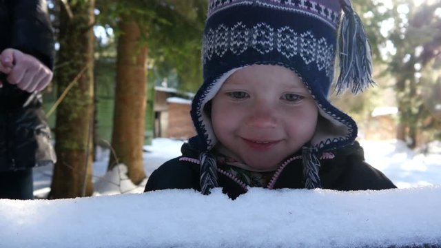 Little child girl licking eating snow in winter forest not afraid of sick