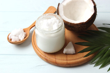 coconuts and coconut oil with tropical leaves on a wooden background