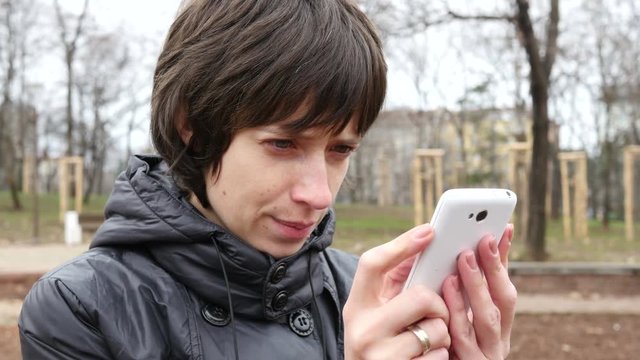 Female type slide her smartphone touchscreen outdoors in park