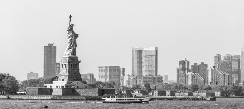 Fototapeta Statue of Liberty with Liberty State Park and Jersey City skyscrapers in background, USA. Black and white image.