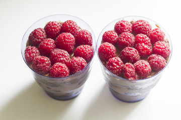 a hand with a beautiful manicure holds a cake in a Cup with berries and chocolate