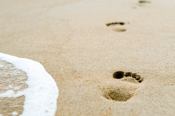 Fototapeta na wymiar footprints in the sand on the beach near the surf