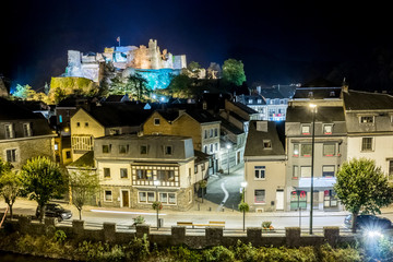Obraz premium Night view of the Belgian city La Roche-en-Ardenne in Wallonia on the embankment of the river Ourthe, picturesque houses and streets with ruins of the medieval castle on the hilltop