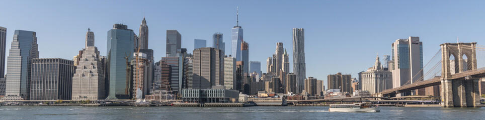 Fototapeta na wymiar Panorama Manhattan skyline under blue sky with East River and Brooklyn Bridge.