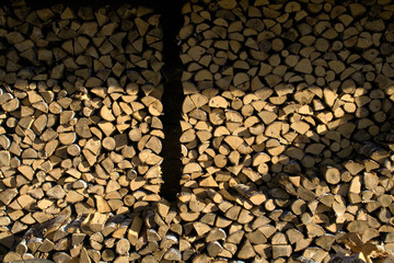 Pile and wall of cut birch wood and stacked wood logs ready for winter, standing on the grass