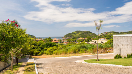 Typical stone pavement street in Buzios, Brazil, with a view to a small village or town, with the ocean and the horizon on the background, with copy space for text